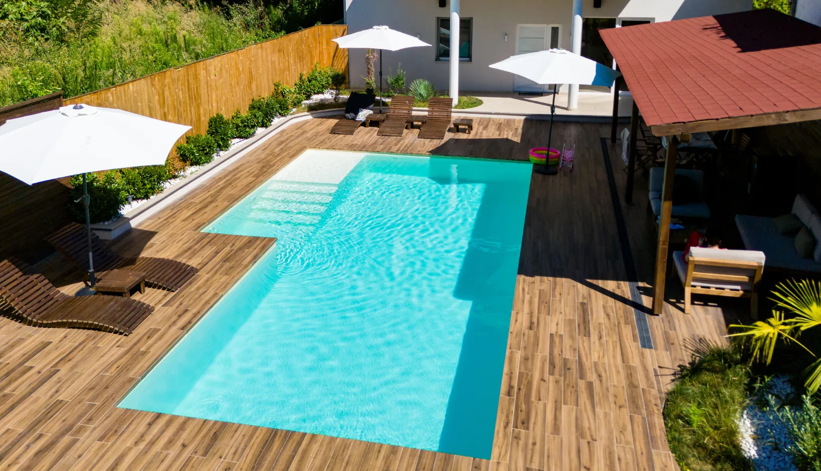 Modern rectangular swimming pool with premium wood decking and integrated lounge area in a Los Angeles backyard.